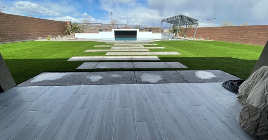 Landscaped back patio leading out to turf lawn and pool.